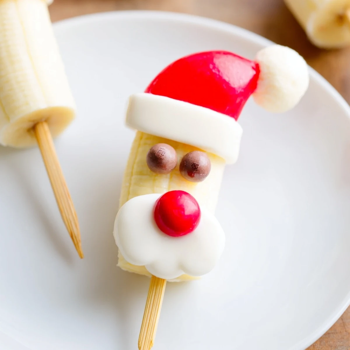 Festive Banana Santa Snack Sticks with strawberry hats and chocolate chip eyes, a perfect holiday treat.