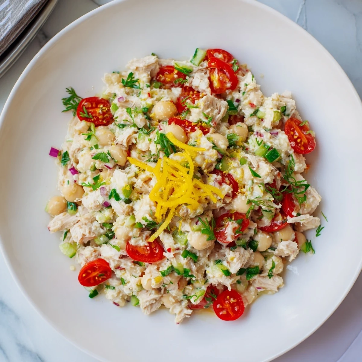 Creamy Dense Chickpea and Tuna Salad, tuna flakes visible with bright red tomatoes and parsley.
