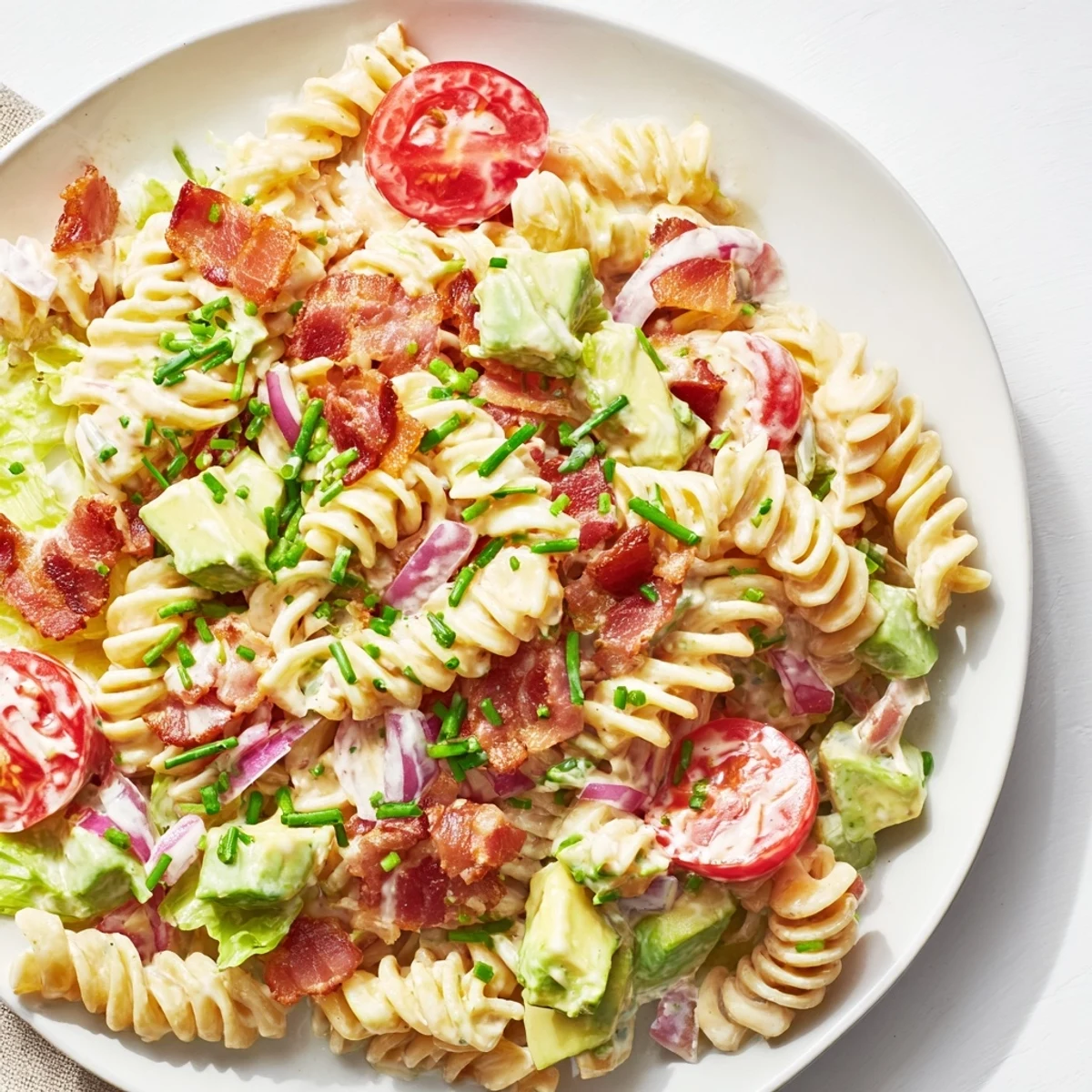 The finished BLT Pasta Salad, ready to serve with a garnish of fresh chives.