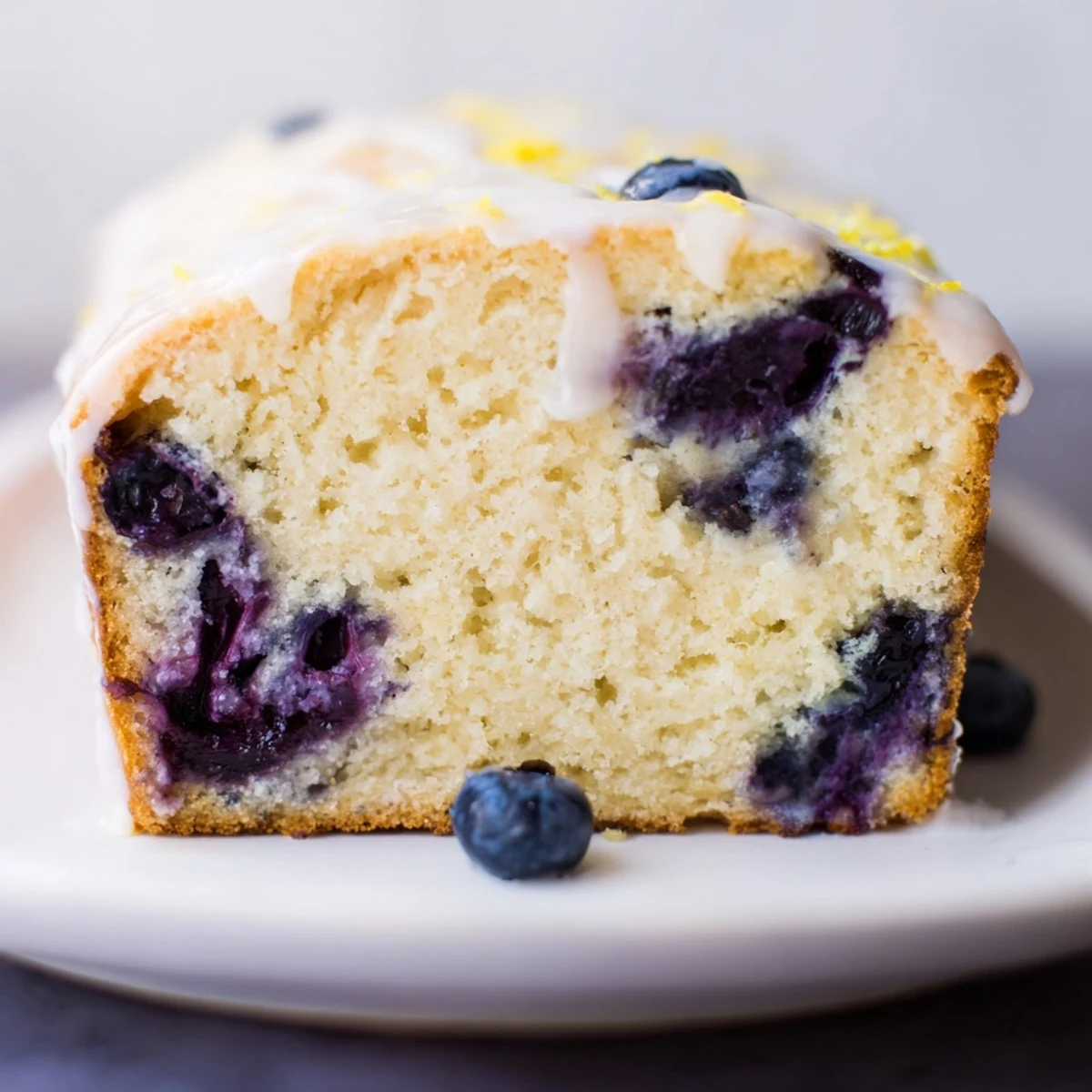 Freshly baked Lemon Blueberry Yogurt Loaf perfect paired with tea, showing visible blueberries and a soft texture.