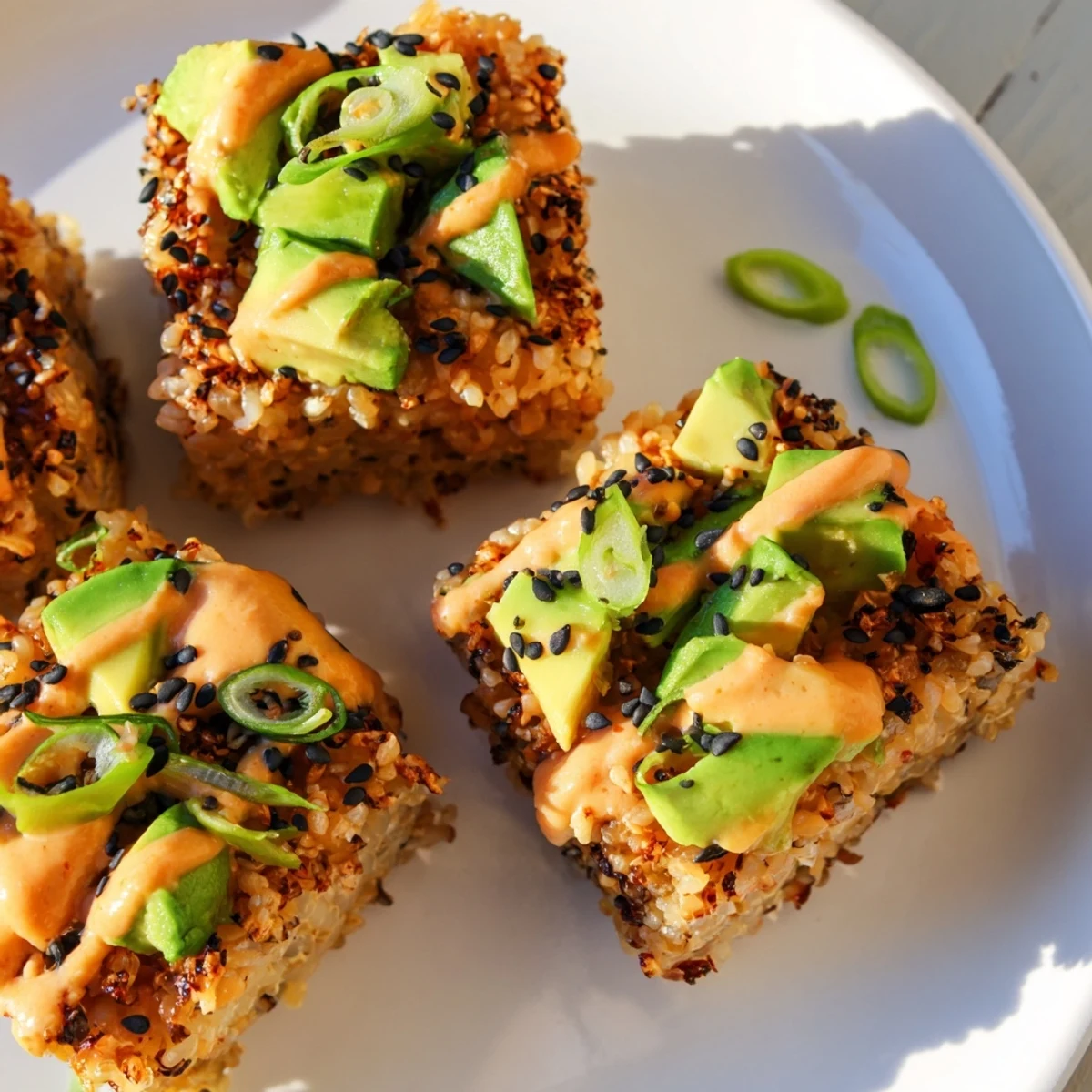 Golden fried Spicy Tuna Crispy Rice appetizers are topped with creamy tuna and avocado, ready to eat.