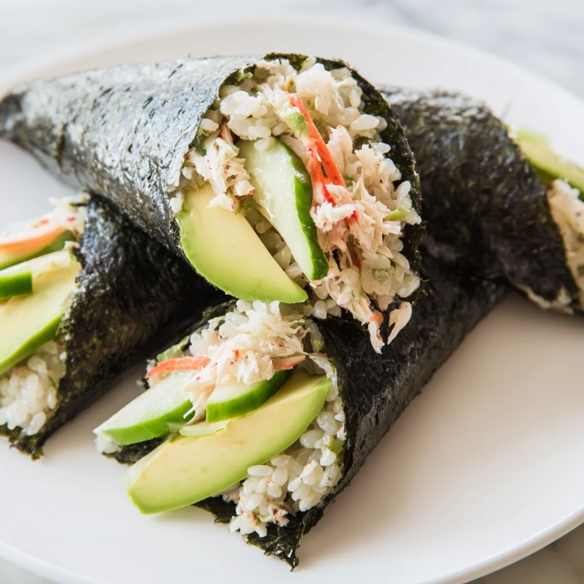 Freshly rolled Sushi Rice Hand Rolls featuring creamy avocado, crisp cucumber, and sweet crab meat nestled in nori.  