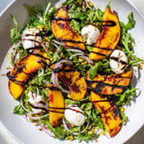 Vibrant grilled peach salad with balsamic glaze, perfect for a light summer meal or appetizer.