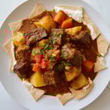 Rich, savory Yemeni Saltah stew featuring tender meat and spiced vegetables, served over bread.