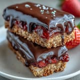 No-bake strawberry oat bars topped with rich chocolate and freeze-dried berries, a satisfying treat for any occasion.
