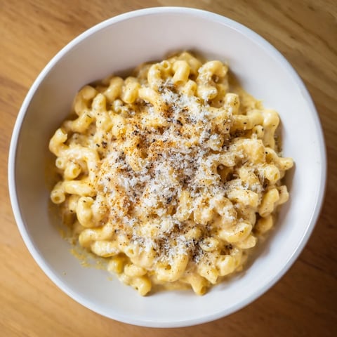 Steaming mug mac & cheese, topped with paprika, ready for a quick, comforting meal.