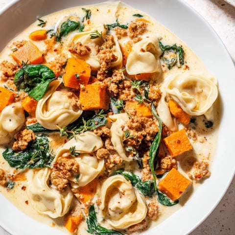 A steaming bowl of Creamy Sausage Tortellini Soup, rich with hearty vegetables and creamy broth.