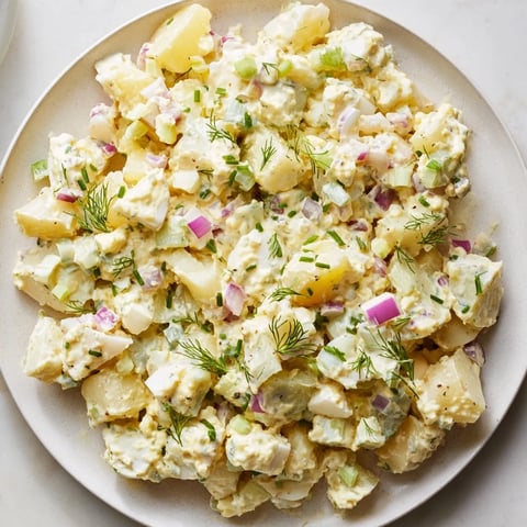 A close-up of creamy chopped egg and potato salad, ready to be enjoyed with fresh chives.