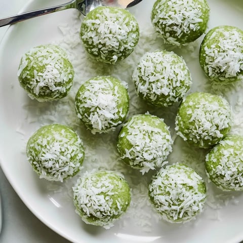 Close-up view of creamy Coconut Matcha Snowball Fat Bombs rolled in delicate coconut flakes.