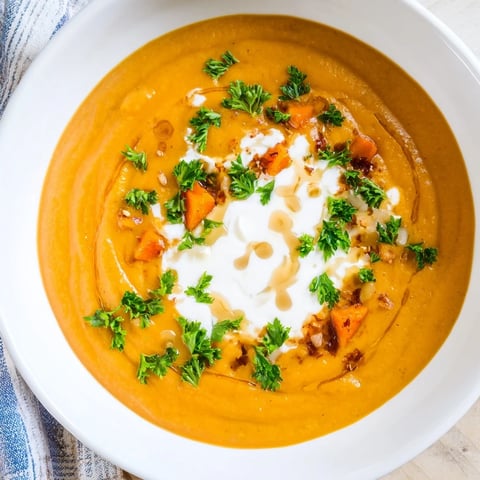 Warm and creamy Sweet Maple Carrot Soup, garnished with fresh parsley, ready to enjoy.