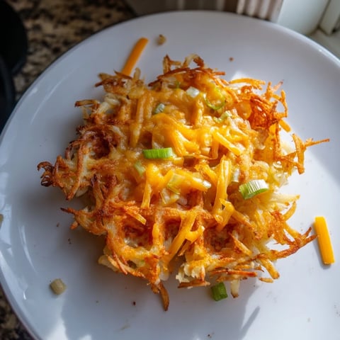 Golden, crispy Cheesy Hash Brown Waffles, topped with sour cream, offering a satisfying crunch.