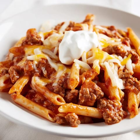 Close-up of a bubbling skillet shows easy beef enchilada pasta, cheesy and savory, ready to serve.