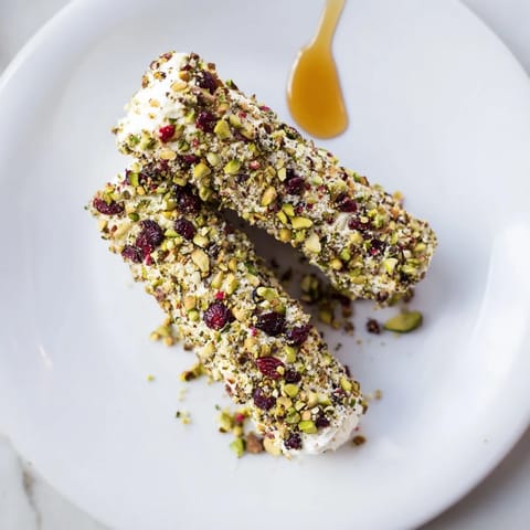 A close-up of festive Cranberry Goat Cheese Logs, creamy cheese coated in bright, sweet cranberries.