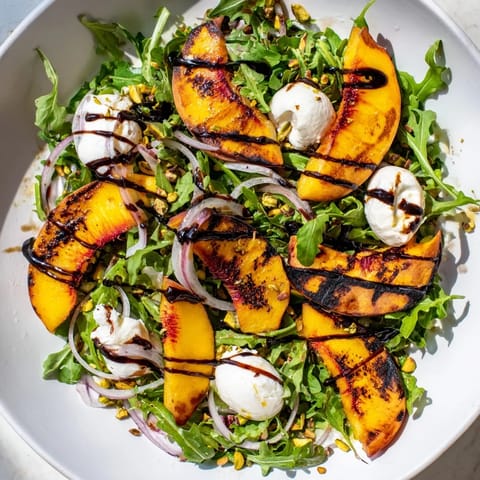 Vibrant grilled peach salad with balsamic glaze, perfect for a light summer meal or appetizer.