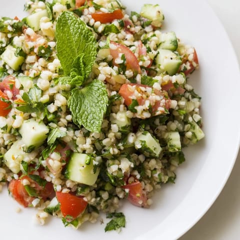 This colorful bowl of Lebanese Tabbouleh Salad features vibrant tomatoes and a zesty lemon dressing.