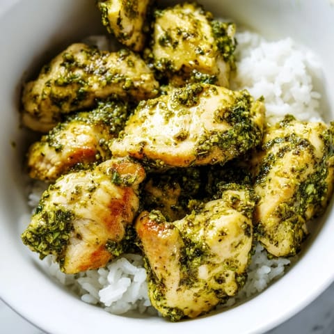 Savory, gluten-free chicken pesto rice bowl topped with toasted pine nuts and a sprinkle of Parmesan for a delightful finish.