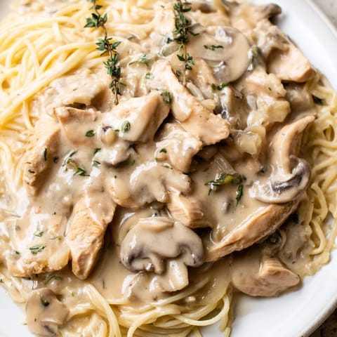 A close-up of creamy mushroom chicken spaghettini, featuring golden-brown chicken, sautéed mushrooms, and a velvety sauce.  