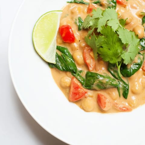 Vibrant chickpea curry simmering in a skillet, with golden coconut milk sauce and aromatic Indian spices filling the pan.  