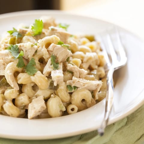 Golden skillet of Green Chili Chicken Mac topped with fresh cilantro and jalapeño slices for a spicy kick.