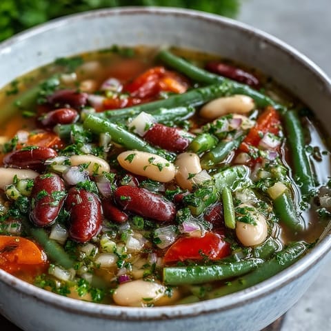 Steaming Three-Bean Salad Soup served in a rustic bowl, featuring red kidney beans, green beans, and creamy cannellini in a vibrant broth.