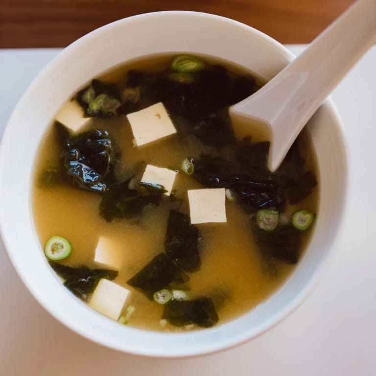 Traditional Miso Soup With Tofu in a rustic ceramic bowl, featuring savory broth and seaweed.