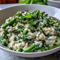 Creamy pea and mint risotto with Parmesan, bright green peas and fresh herbs in a rich, savory Italian dish.