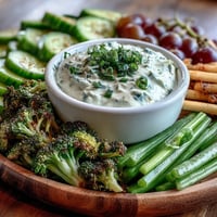 A vibrant green snacks board with crisp cucumber, snap peas, and creamy avocado ranch dip.  
