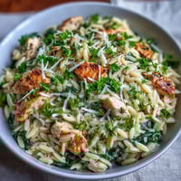 Lemon Orzo with Chicken and Spinach in a creamy skillet, garnished with fresh parsley and lemon zest.